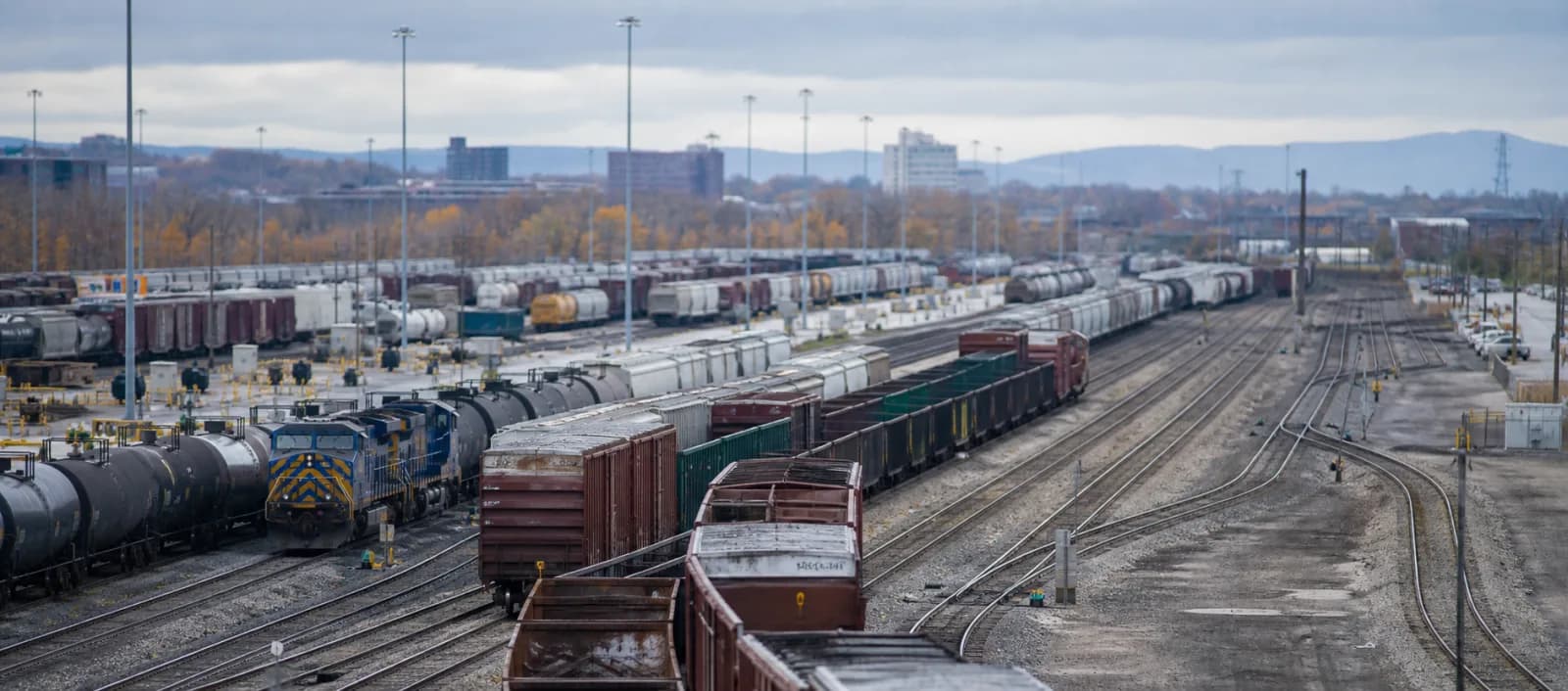 Parallel tracks, locomotives, and freight cars in a large rail yard.